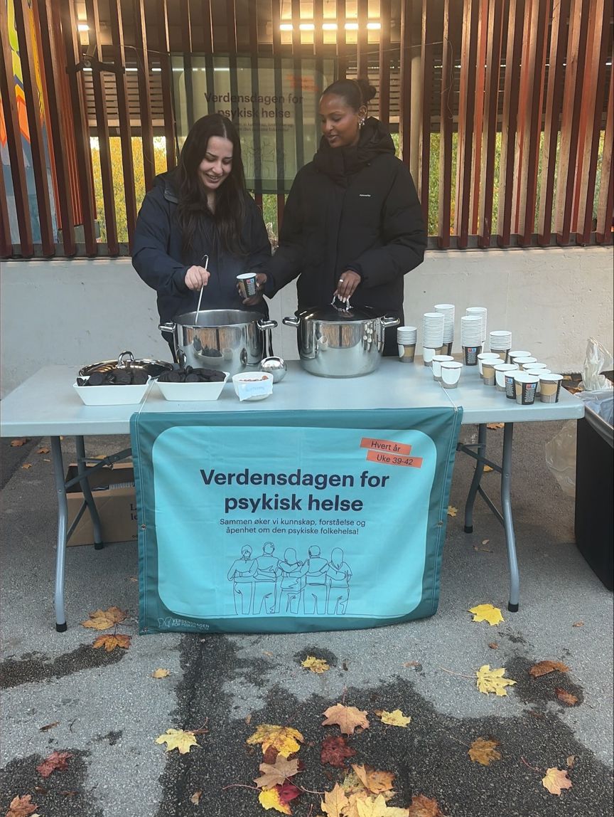 En person og en person står bak et bord med mat og drikke